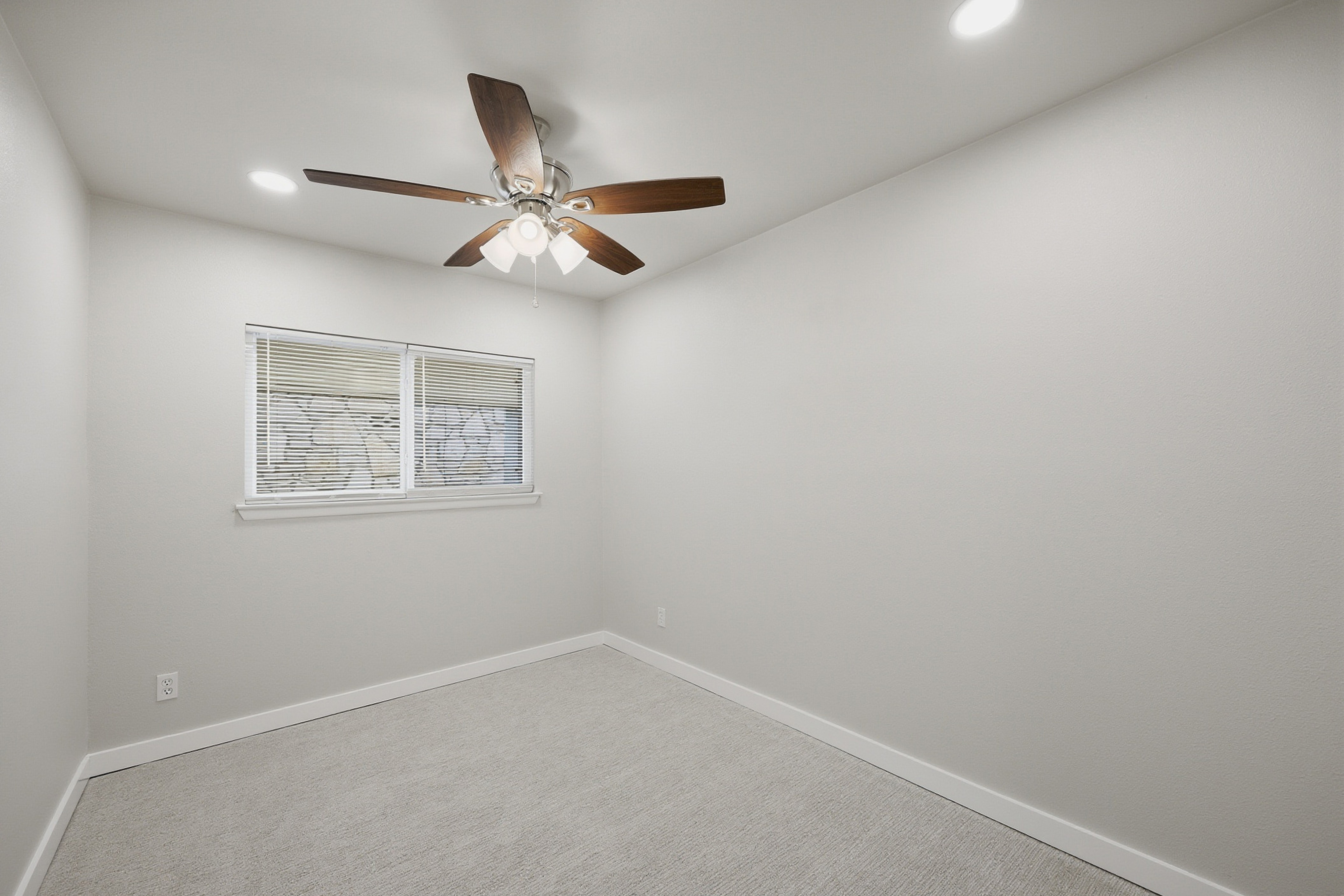 Secondary bedroom with ceiling fan, front-facing window, and neutral carpet